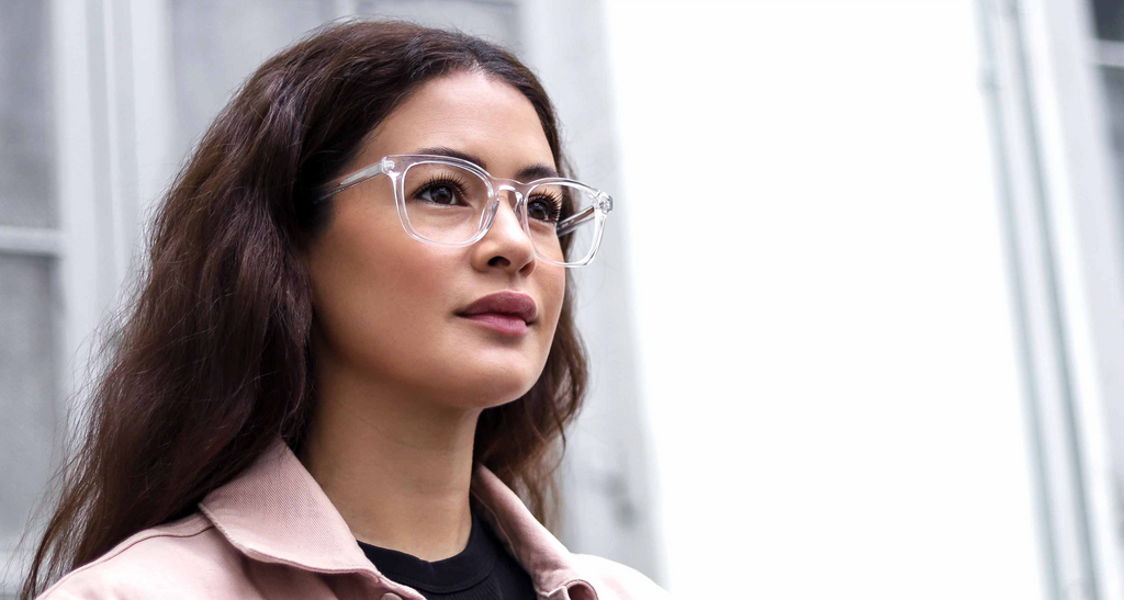 A stylish woman wearing glasses and a jacket, showcasing the latest eyeglass trends for 2025.