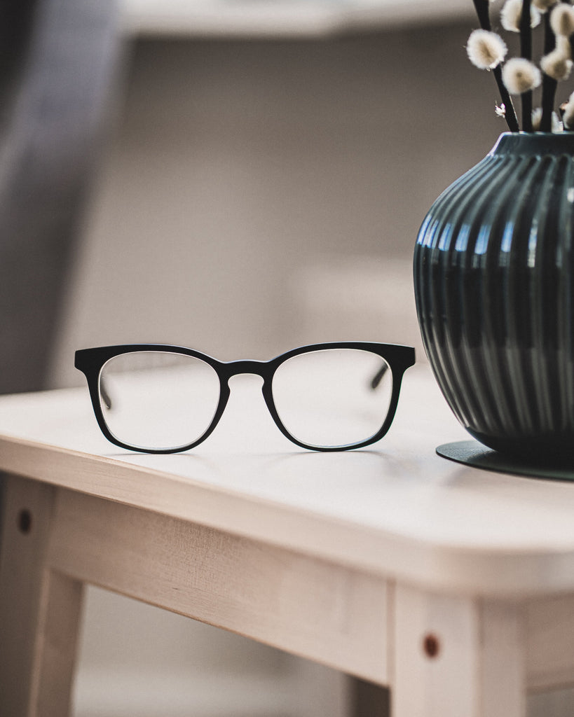 Black Luxreaders reading glasses on the top of a wooden table