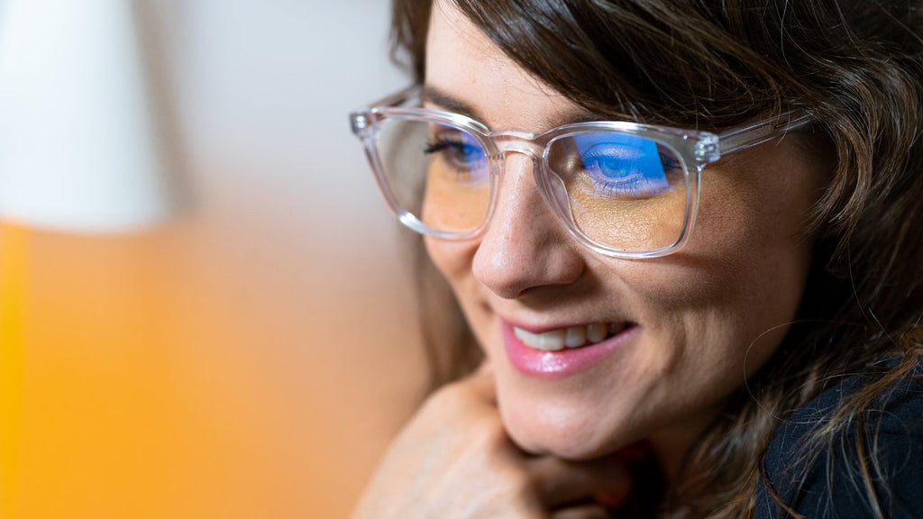 Woman with glasses smiling in stylish blue light frames.