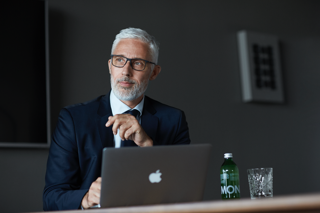 A man in a suit and glasses works on a laptop, representing "6 tips to find the perfect frame for your eyeglasses online."